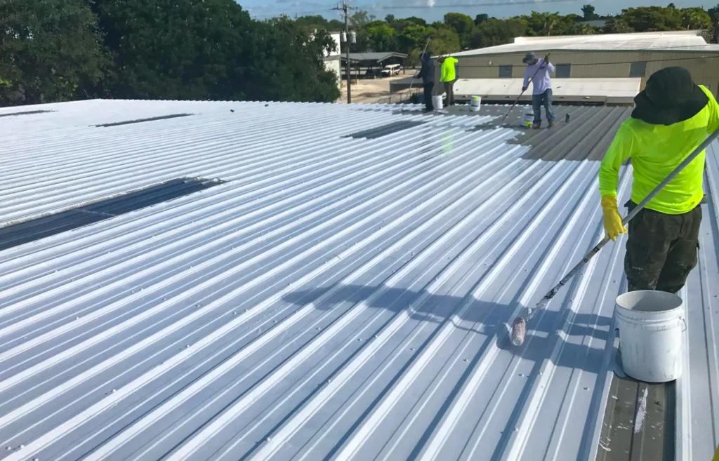 Roofer rolling roof coating over metal roof in Mountain Grove, MO.