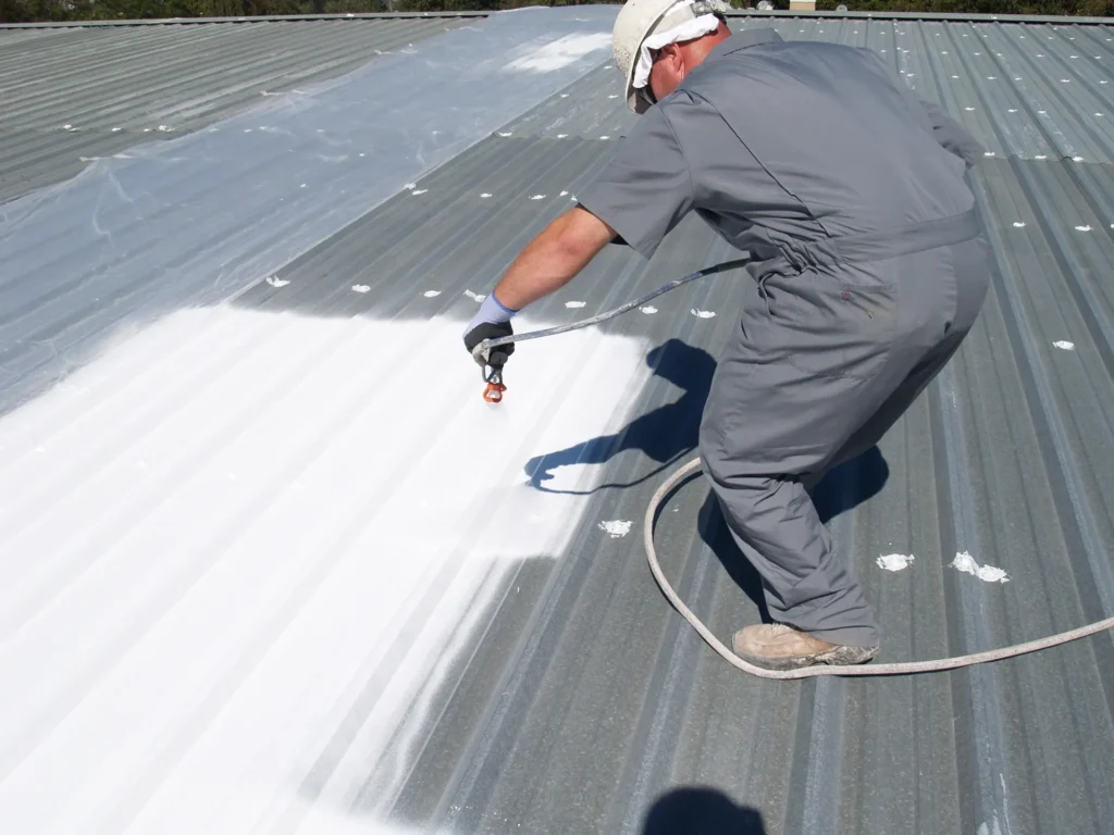 Roofer spray coating over metal roof in Ava, MO